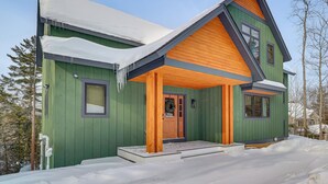 A green wooden house with a sloped roof and a front porch. - Luxe Mountain Home w/ Chefs Kitchen & Okemo Views (Ludlow)