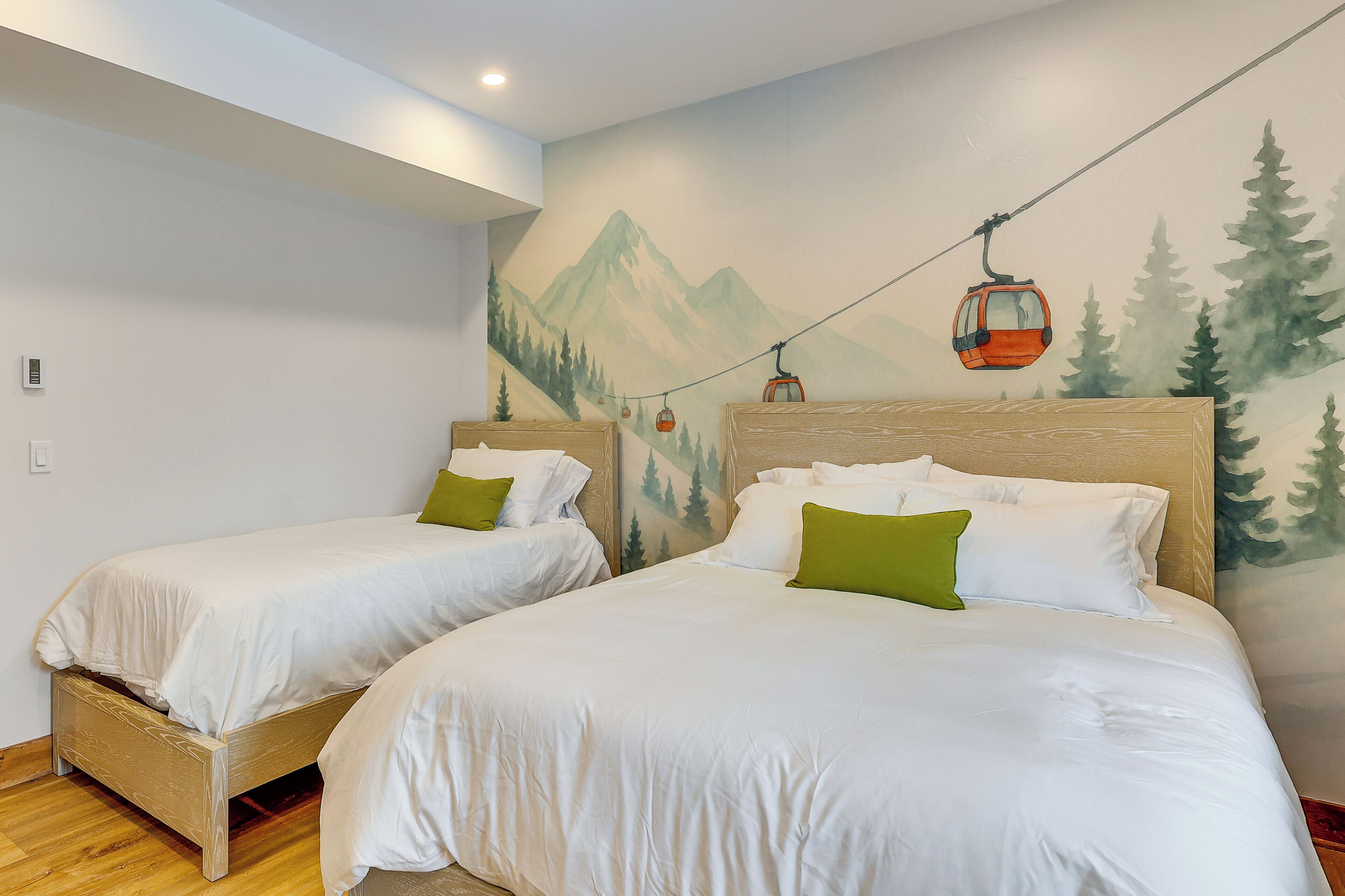 A hotel room with two beds, a mural of a mountain and forest, and a cable car on the wall.