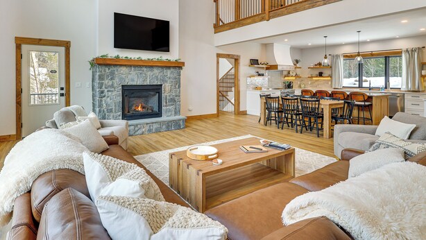 A spacious living area with a fireplace, a dining area, and a kitchen. - Luxe Mountain Home w/ Chefs Kitchen & Okemo Views (Ludlow)