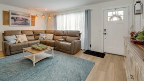 En moderne stue med en brun hjørnesofa, et træsofabord og en blå måtte.