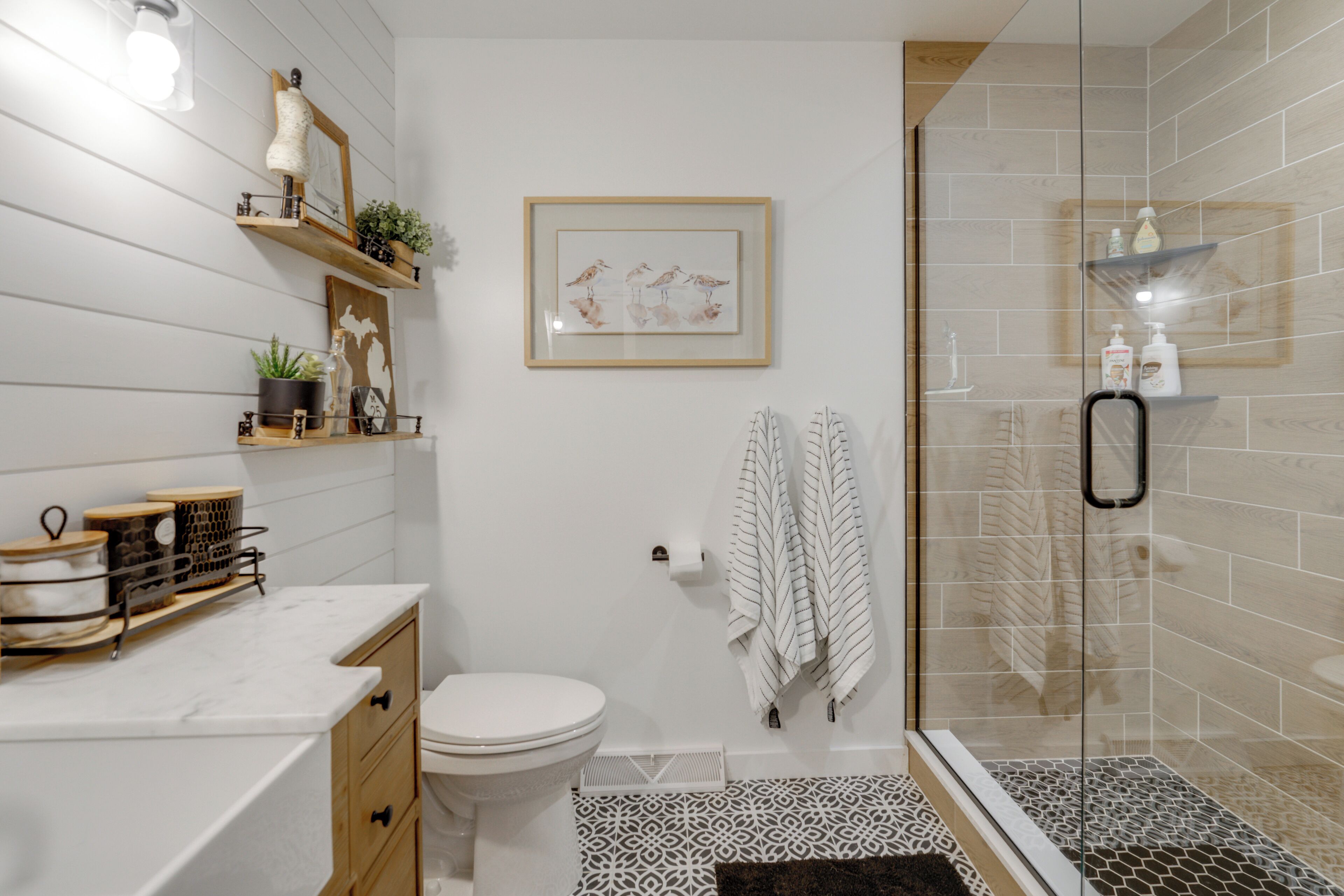 A modern bathroom with a toilet, shower, and decorative shelves.