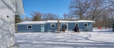 A two-story house with a snow-covered yard and a clear blue sky.