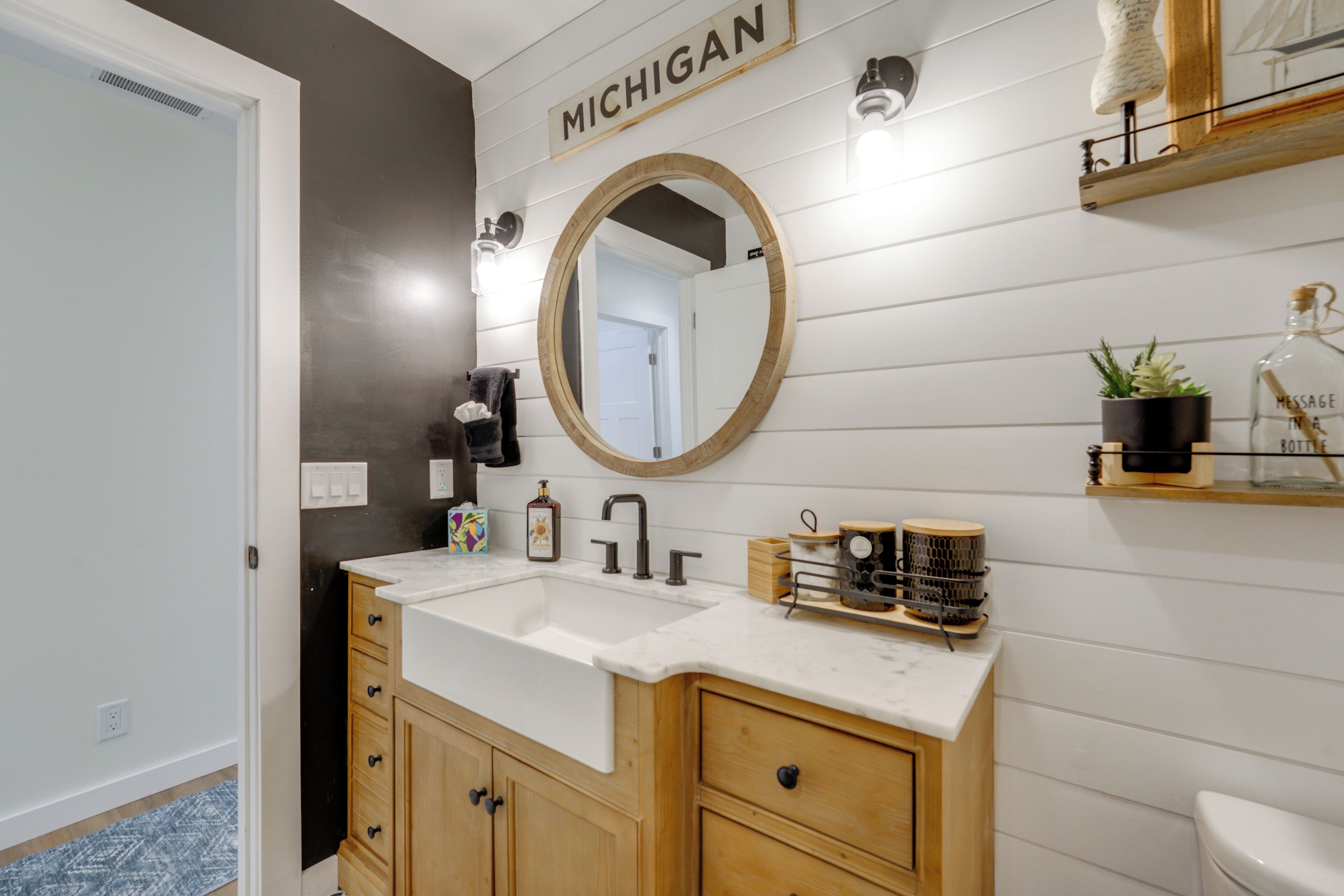 Une salle de bain avec un meuble-lavabo en bois, un grand miroir et une enseigne sur laquelle on peut lire « MICHIGAN ».