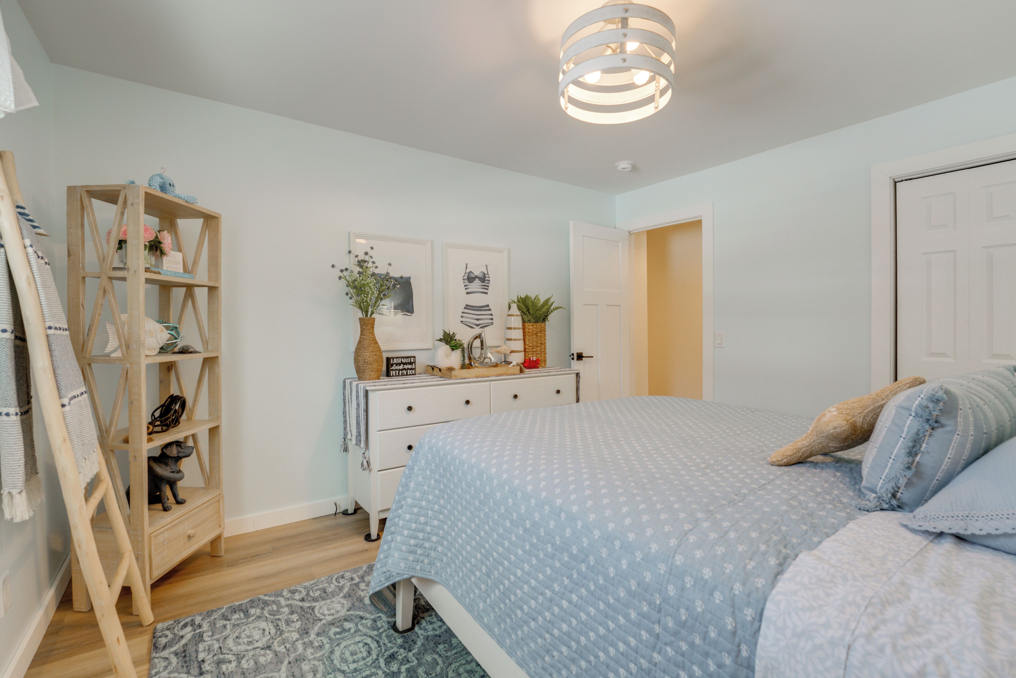 Un dormitorio con cama, cómoda, escalera de madera y adornos en la pared.