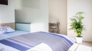 Une chambre d’hôtel moderne, équipée d’un lit, d’une petite table et d’une plante en pot.