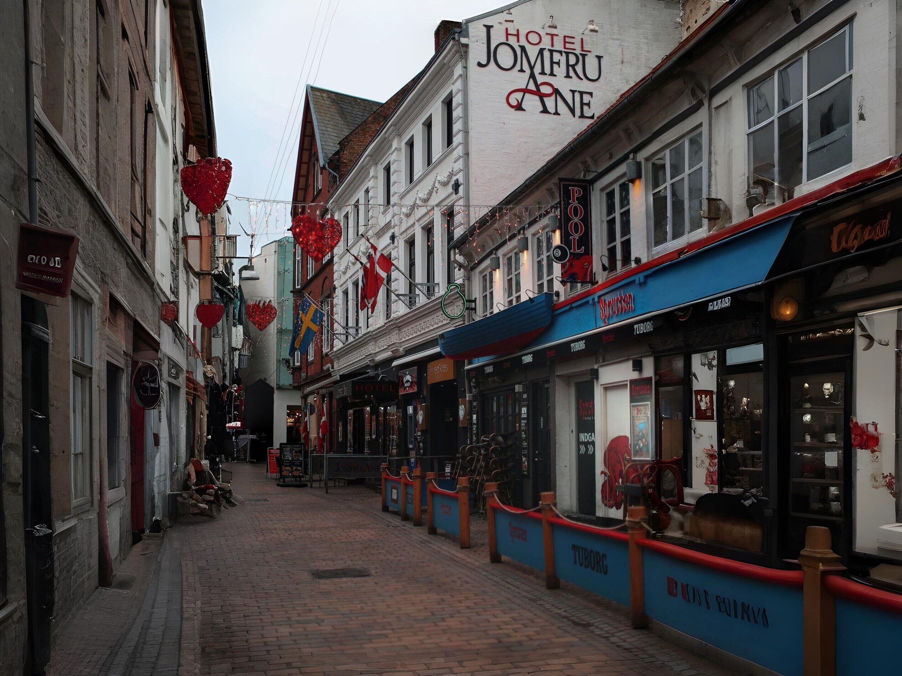 A narrow street lined with buildings, including a hotel named 'Hotel Jomfru Ane'.