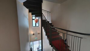 A staircase with a red carpet, black railing, and a hand holding a key. - Dancenter Hotel Jomfru Ane Standard Double (Aalborg)