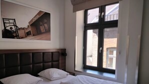 A hotel room with a bed, a headboard, a window, and a wall-mounted picture. - Dancenter Hotel Jomfru Ane Standard Double (Aalborg)