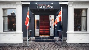 The entrance of Hotel Jomeroane with a red door, two flags, and a signboard. - Dancenter Hotel Jomfru Ane Standard Double (Aalborg)