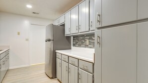 A modern kitchen with white cabinets, a stainless steel refrigerator, and a tiled backsplash. - Artistic Escape in Fayetteville! Cozy Couple's Apt (Fayetteville)