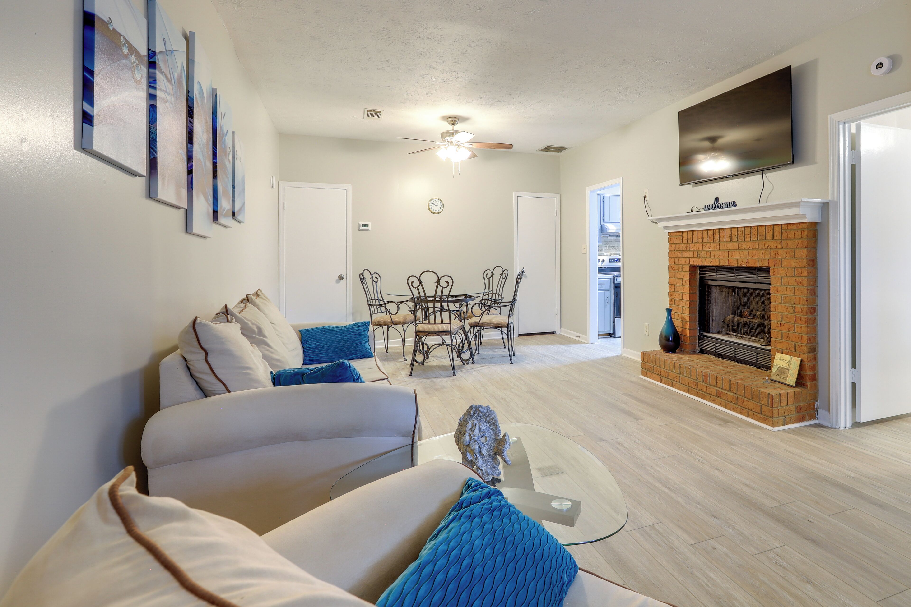 A living room with a fireplace, a dining table with chairs, and a sofa with cushions.
