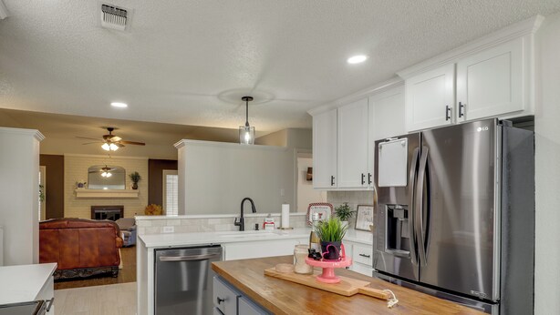 A modern kitchen with white cabinets, a stainless steel refrigerator, and a wooden countertop. - Near Attractions: Family-friendly Lubbock Home! (Lubbock)