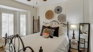 A neatly arranged bedroom with a bed, bedside table, lamp, and decorative wall hangings. - Near Attractions: Family-friendly Lubbock Home! (Lubbock)