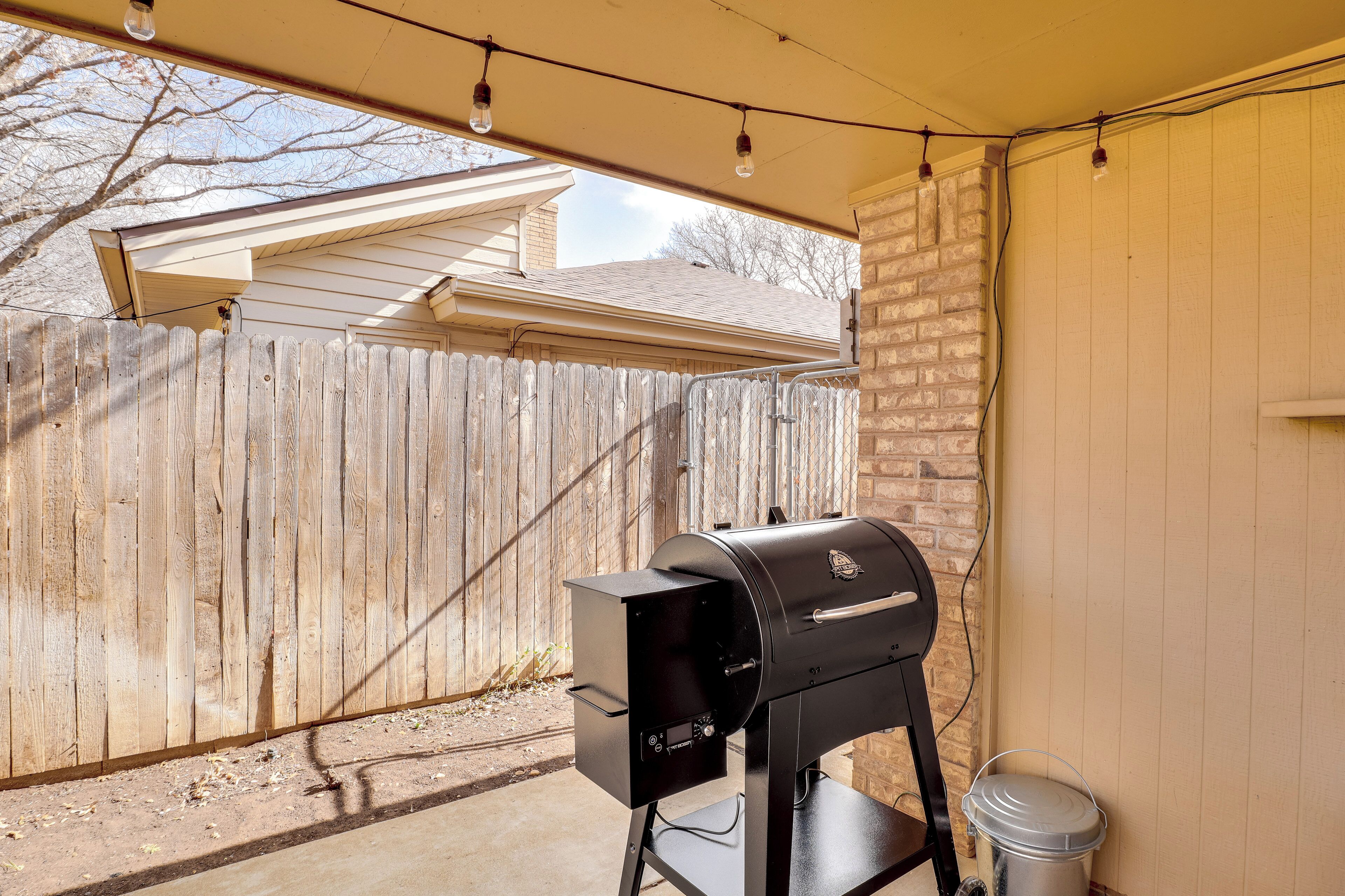 Un barbecue dans un jardin, avec une clôture en bois et une porte de garage.