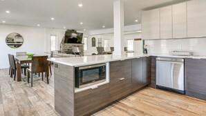 A modern kitchen with a central island, built-in microwave, and dishwasher. - Family Summer Getaway w/ Hot Tub on Lake Hopatcong (Lake Hopatcong)