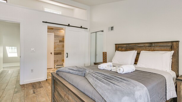 A bedroom with a large bed, wooden headboard, and a built-in wardrobe. - Family Summer Getaway w/ Hot Tub on Lake Hopatcong (Lake Hopatcong)