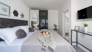 Une chambre moderne avec un grand lit, une table de chevet, une télévision et une vue sur le balcon.
