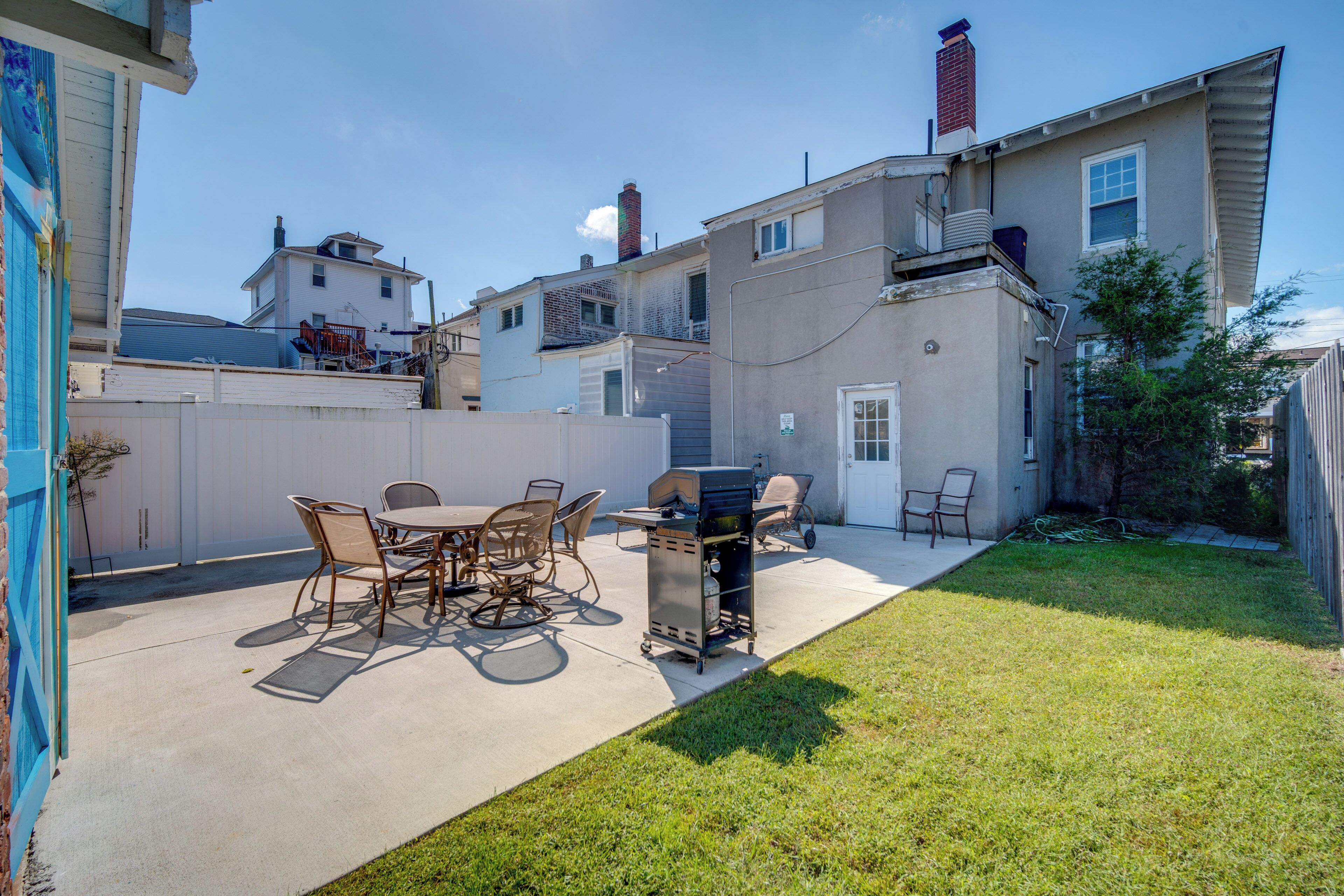 A backyard with a barbecue grill, dining table, and chairs.