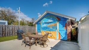 A backyard with a patio table and chairs, a barbecue grill, and a mural on the garage door. - 2 Blocks to Beach & Boardwalk: Ventnor City Escape (Ventnor City)