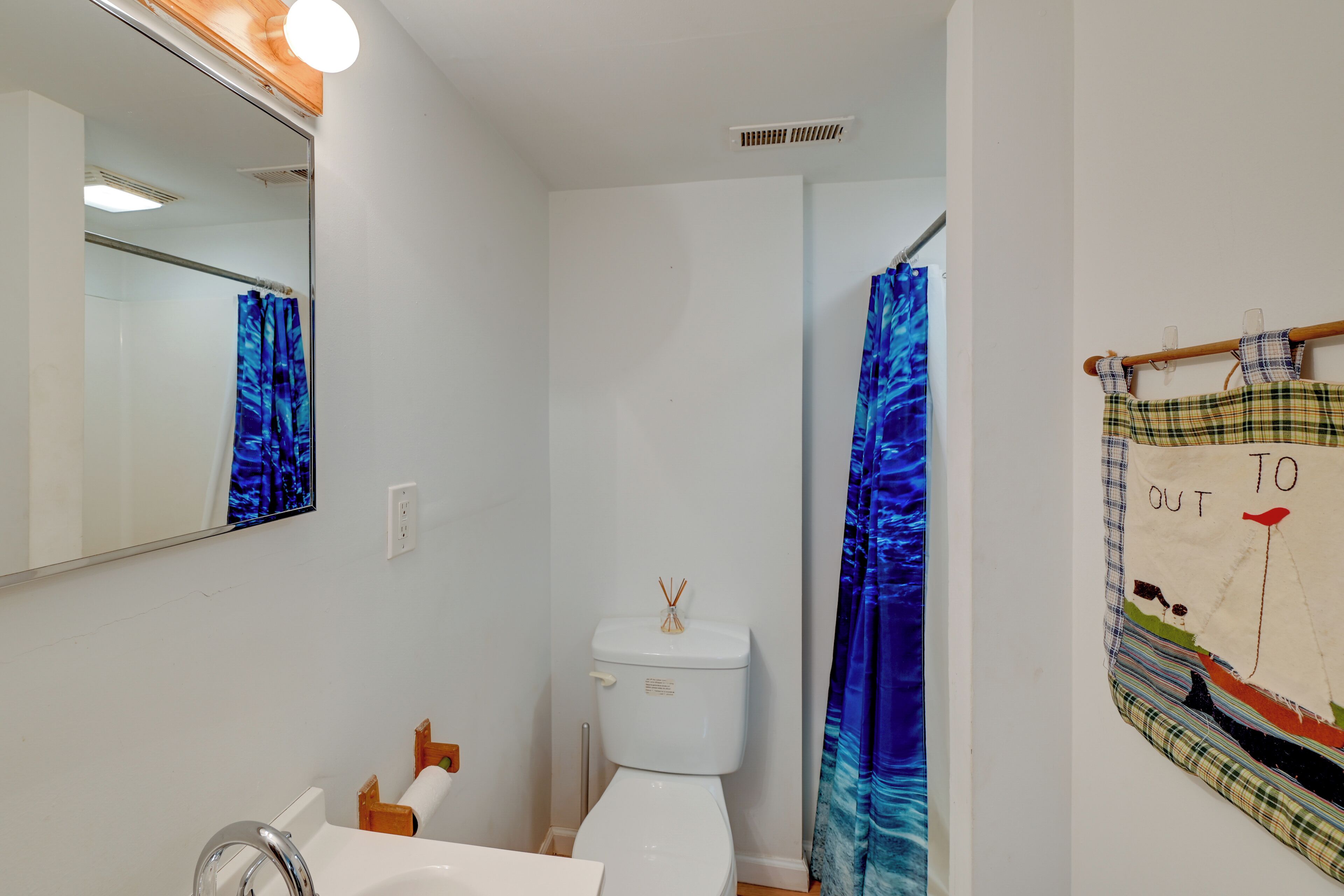 A bathroom with a white toilet, a sink, a mirror, and a shower curtain.