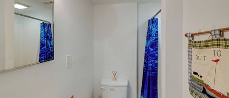 A bathroom with a white toilet, a sink, a mirror, and a shower curtain.