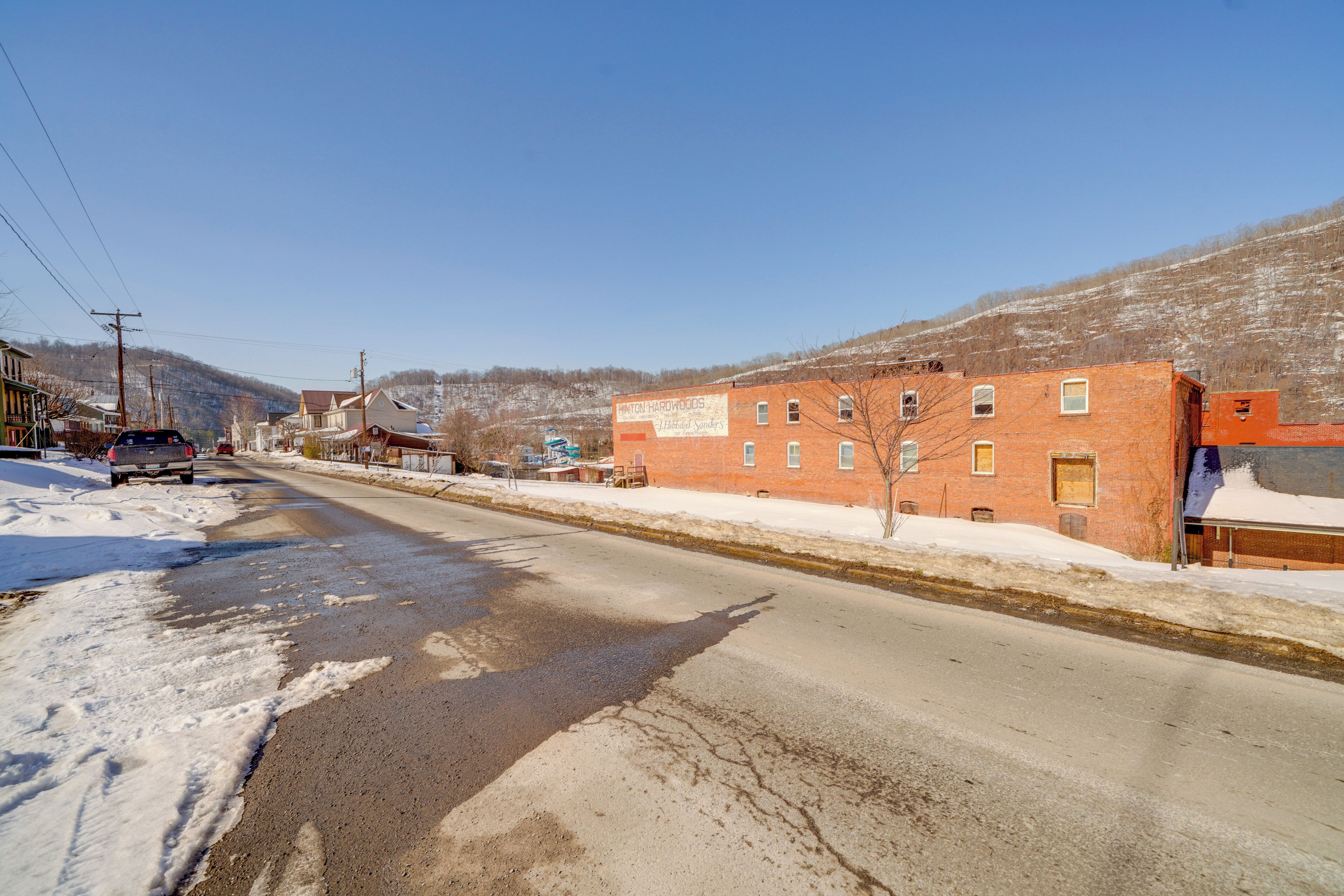 Una calle cubierta de nieve con un edificio de ladrillo que dice 'Hunting Hardwoods'.