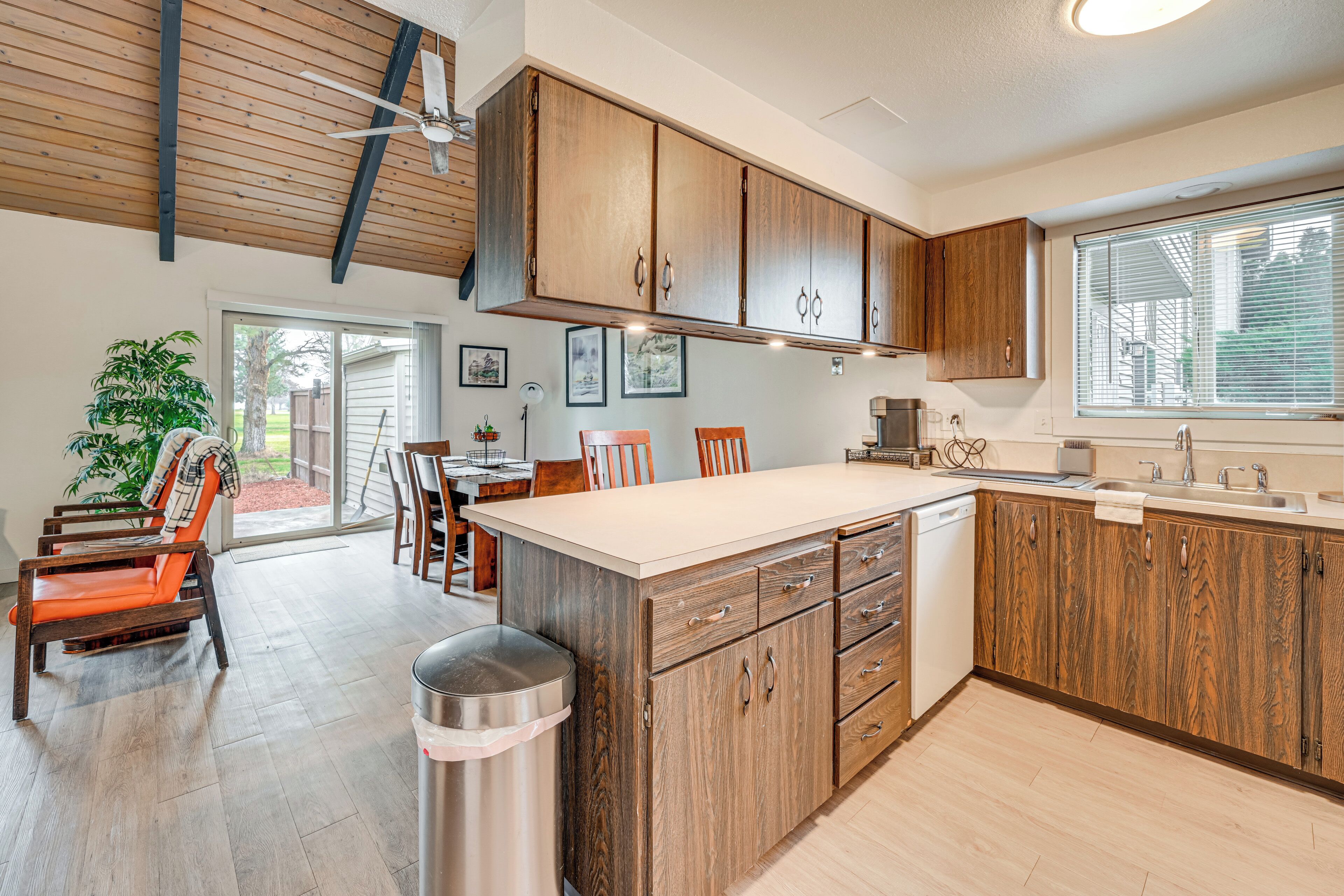 A modern kitchen with wooden cabinets, a large island, and a dining area with chairs and a table.