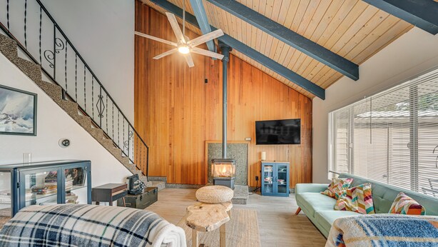A cozy living room with a fireplace, a staircase, and a large window. - Near Mcnary Dam! Pet-friendly Condo on Golf Course (Umatilla)