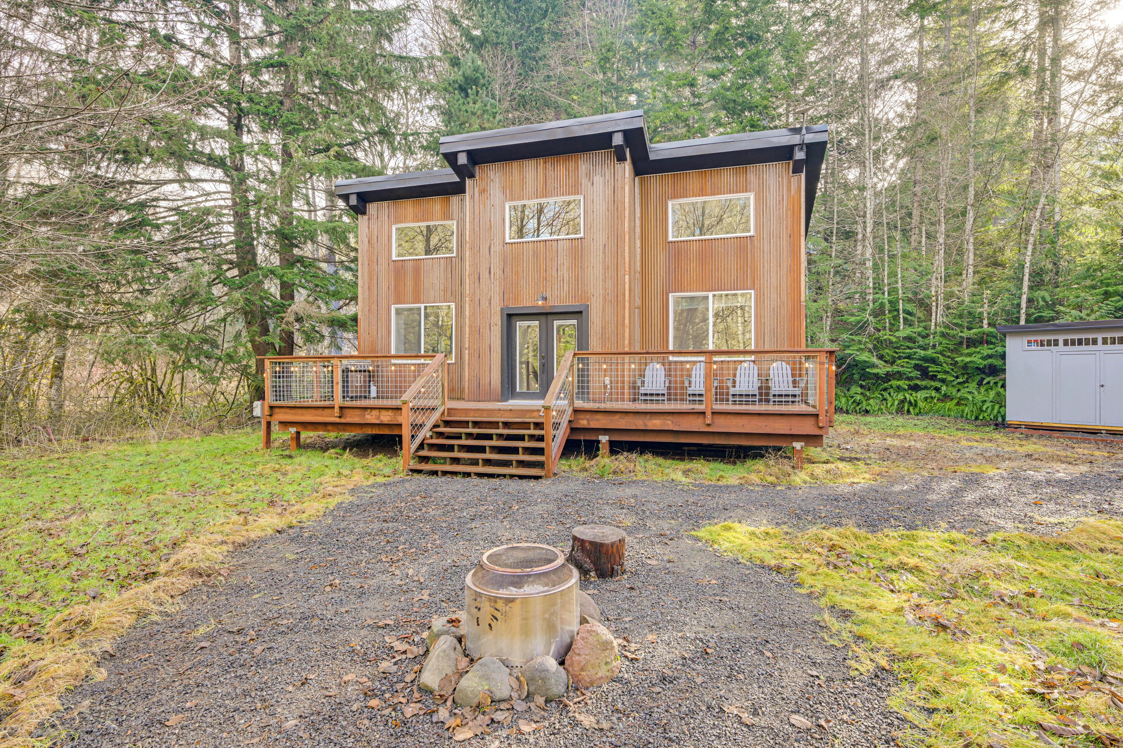 Une cabane en bois à deux étages, dotée d’une terrasse et entourée de forêt.