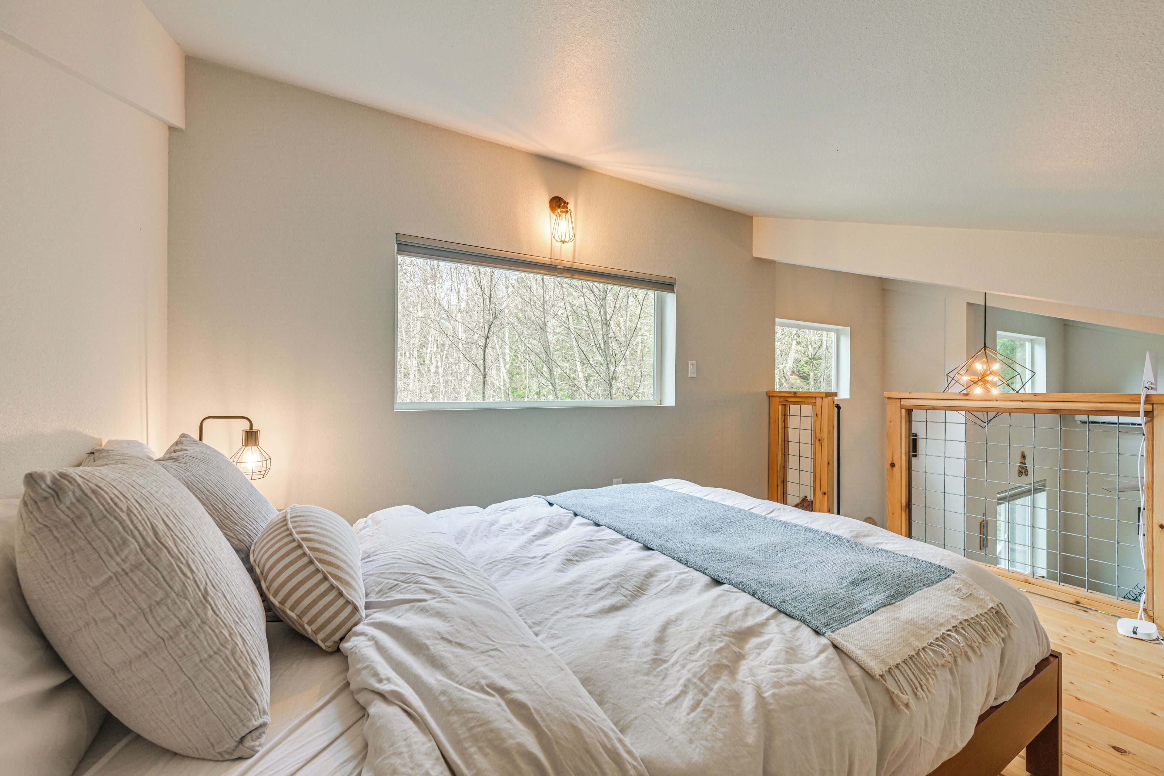 A bedroom with a large bed, a window, and a view of trees.
