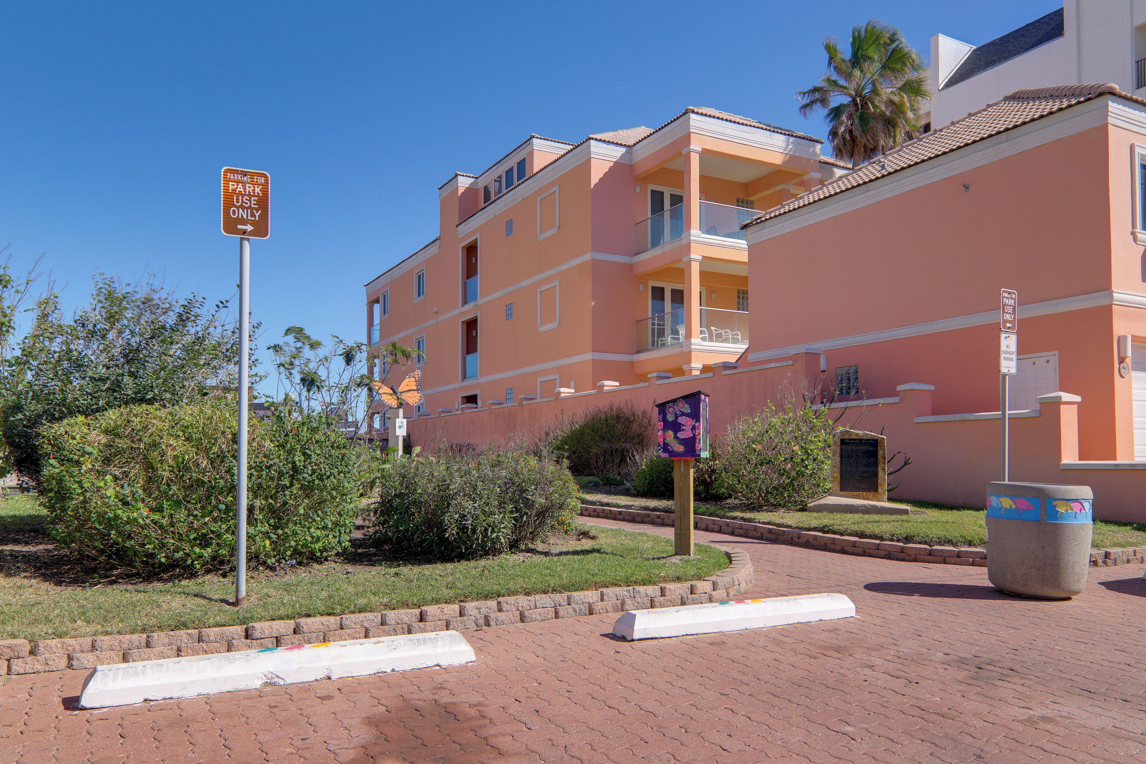 A multi-story residential building with balconies and a parking area.