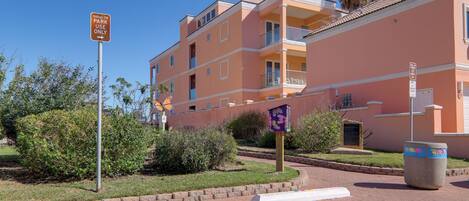 A multi-story residential building with balconies and a parking area.