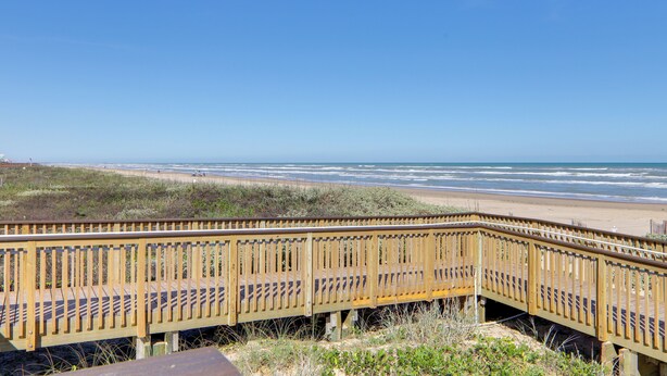 Un paseo marítimo de madera que conduce a una playa con vista despejada al océano.