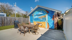 A patio with a table and chairs, a grill, and a mural on the garage door. - 2 Blocks to Ventnor City Beach: Pet-friendly Gem! (Ventnor City)