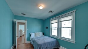 A bedroom with teal walls, a wooden floor, a bed with a blue bedspread, and a window with blinds. - 2 Blocks to Ventnor City Beach: Pet-friendly Gem! (Ventnor City)