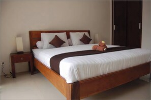 A neatly made bed with a wooden frame, white bedding, and brown pillows. - 3 BR, 250 Sqmt Villa, Terrace, 10 min Available (Canggu)