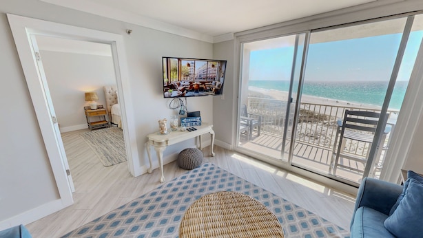 A room with a large window, a television, a small table, and a sofa. - Destin On The Gulf 506 2 Bedroom Condo (Destin)
