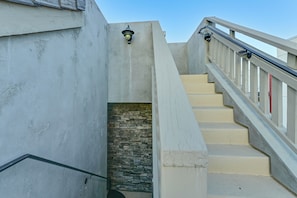 A concrete staircase with a metal handrail and a stone wall at the bottom. - Stroll to Shore: Oceanside Condo w/ Hot Tub Access (Oceanside)