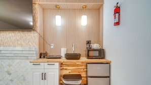 Une cuisine compacte dotée d’un plan de travail en bois, d’un four à micro-ondes, d’une machine à café et d’une poubelle.