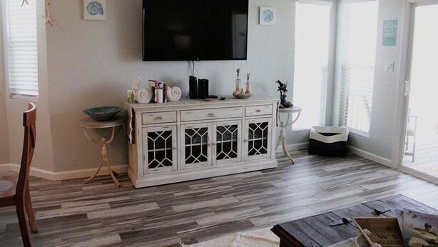 Un salon avec un meuble blanc, un téléviseur à écran plat et un plancher en bois.