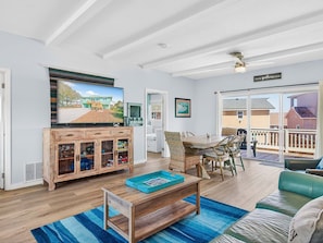 A spacious living room with a wooden coffee table, a television mounted on the wall, and a dining area with a table and chairs. - Barefoot At The Lehmans Rp14 4 Bedroom Home (Rockport)