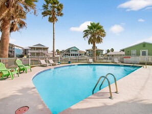 A swimming pool with lounge chairs, palm trees, and beachfront buildings. - Lighthouse Landing At Kontiki Kc111 1 Bedroom Condo (Rockport)