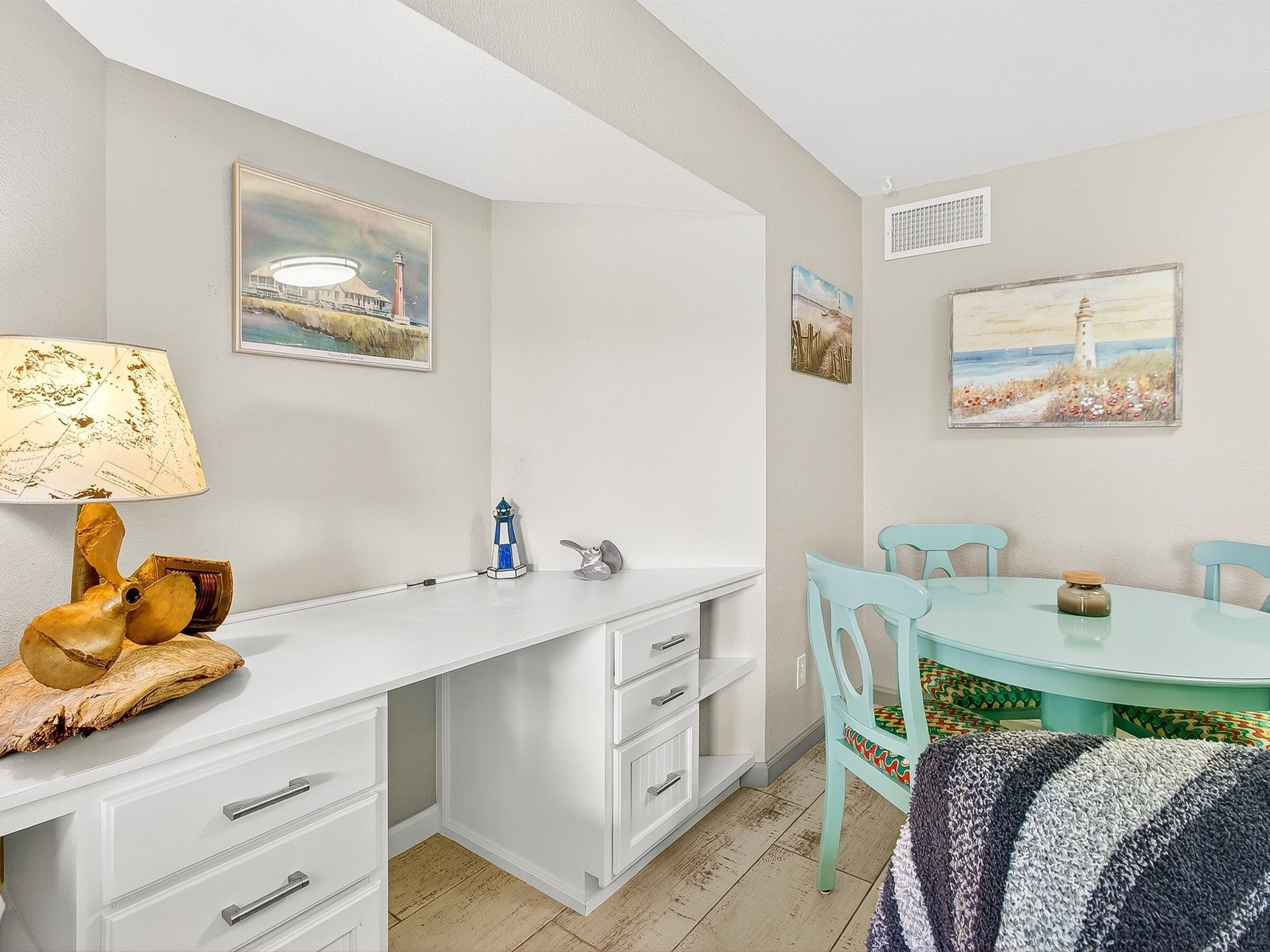 A compact kitchen with white cabinetry, a dining table with chairs, and artwork on the walls.