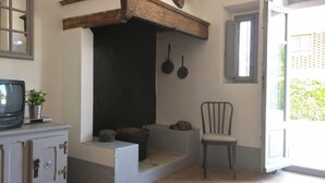 A cozy room with a fireplace, a television on a cabinet, and a chair. - Walnut – Tuscan 2 bedroom apartment on the ground floor with panoramic pool (Castelfiorentino)