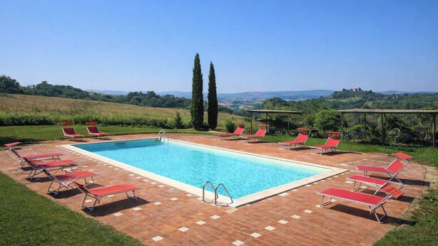 A rectangular swimming pool with a clear blue water, surrounded by red lounge chairs and a brick deck. - Walnut – Tuscan 2 bedroom apartment on the ground floor with panoramic pool (Castelfiorentino)