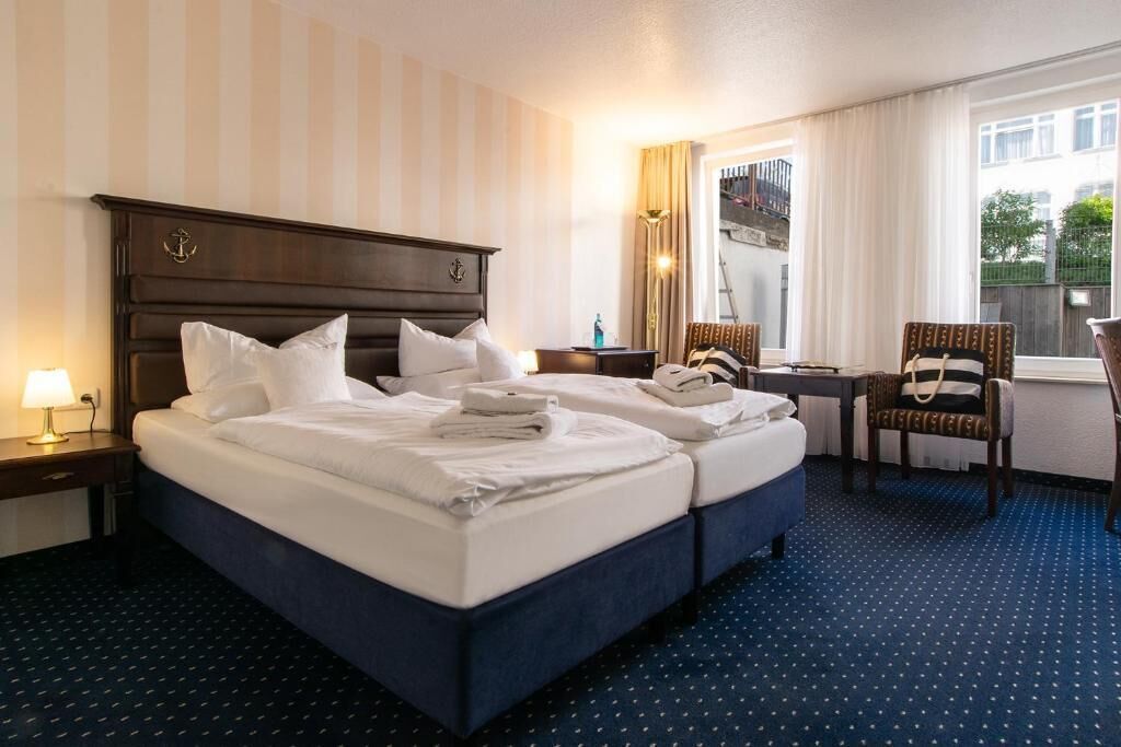 A hotel room with a large bed, two bedside tables, a desk, and a chair.