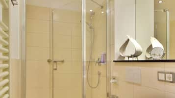 A modern bathroom with a glass shower enclosure, a toilet, and a vanity with a mirror.