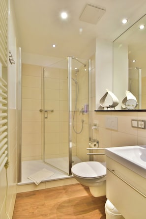 Un baño moderno con cabina de ducha de vidrio, inodoro y tocador con espejo.