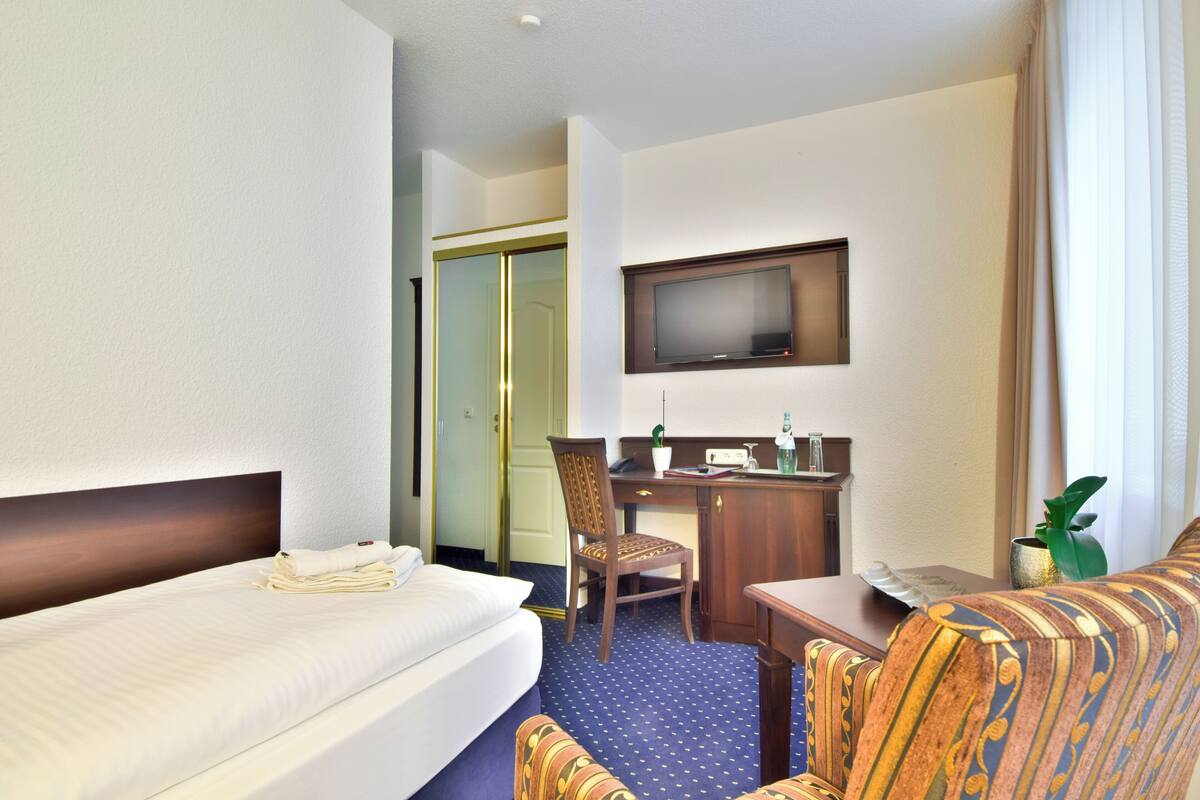 Une chambre d’hôtel avec un lit, un bureau, une chaise, une télévision et une petite table.