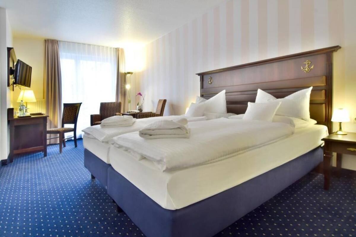 Une chambre d’hôtel avec un grand lit, un bureau avec une lampe, une chaise et un téléviseur.